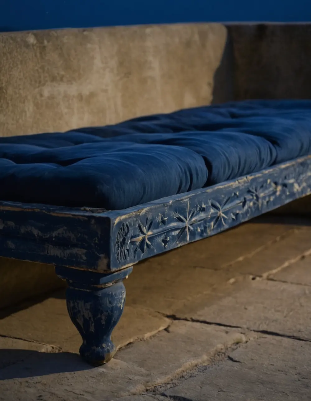 Purva Phalguni: front legs of a daybed on a stone ledge at night